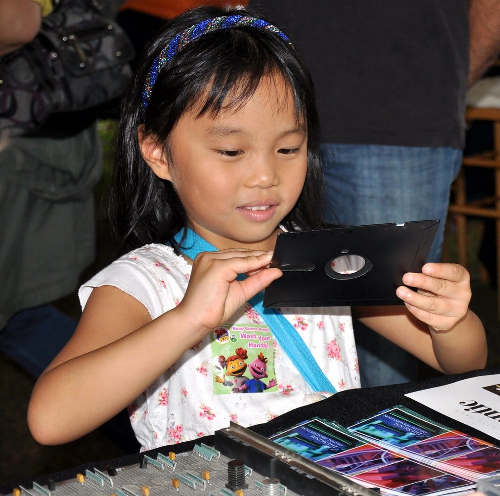 Imagem de uma criança curiosa interagindo com um disquete.