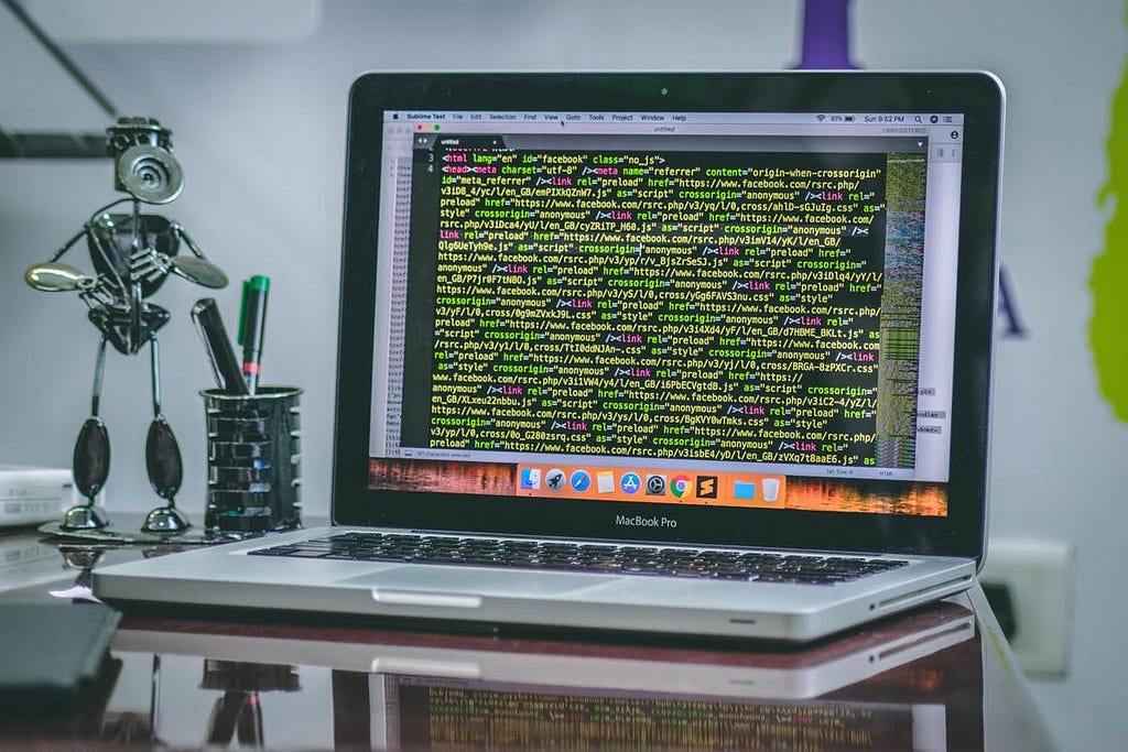 A shot of a small desk with a laptop computer screen crowded by code.