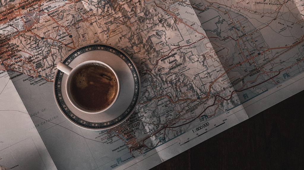 A cup of coffee sitting on a saucer that is sitting on a highway map
