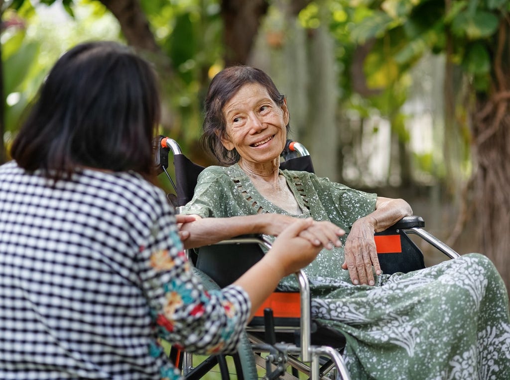 Elderly woman in a wheelchair looks at her daughter, Photo by Toa55/Getty Images