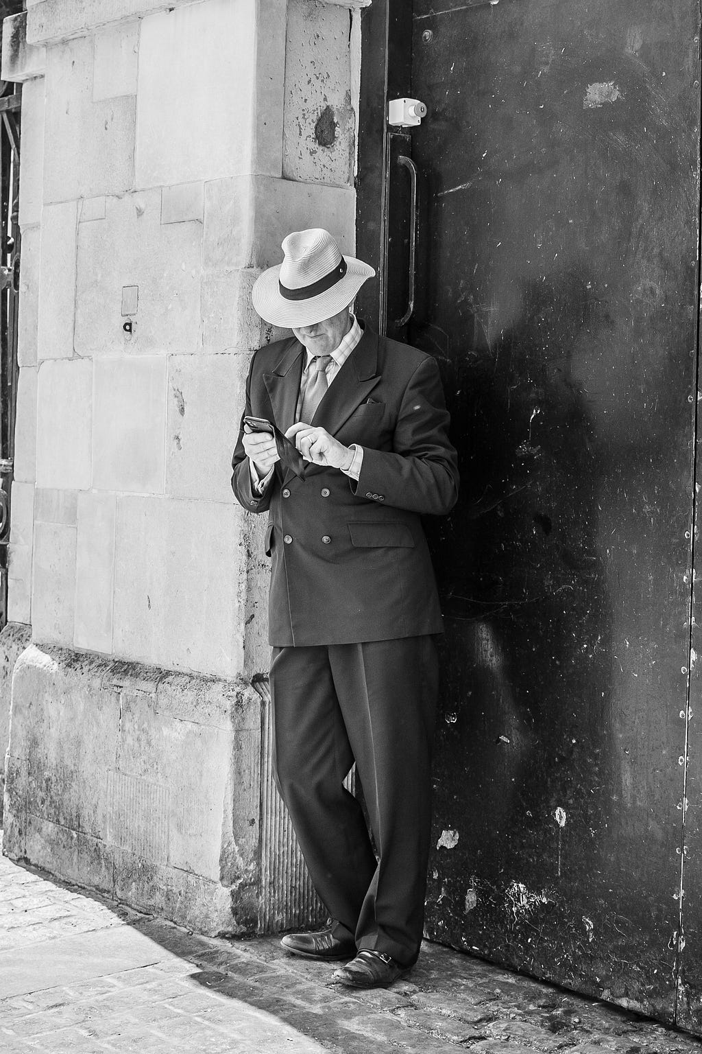 Gangster wearing 1930’s suit and Panama stood in a doorway.