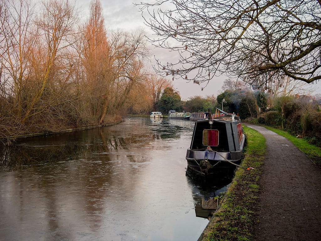 an english canal showing a narrowboat and trees