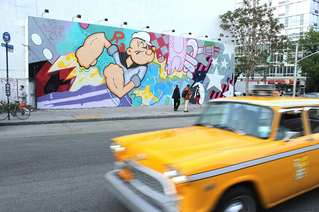 yellow taxi with street art behind