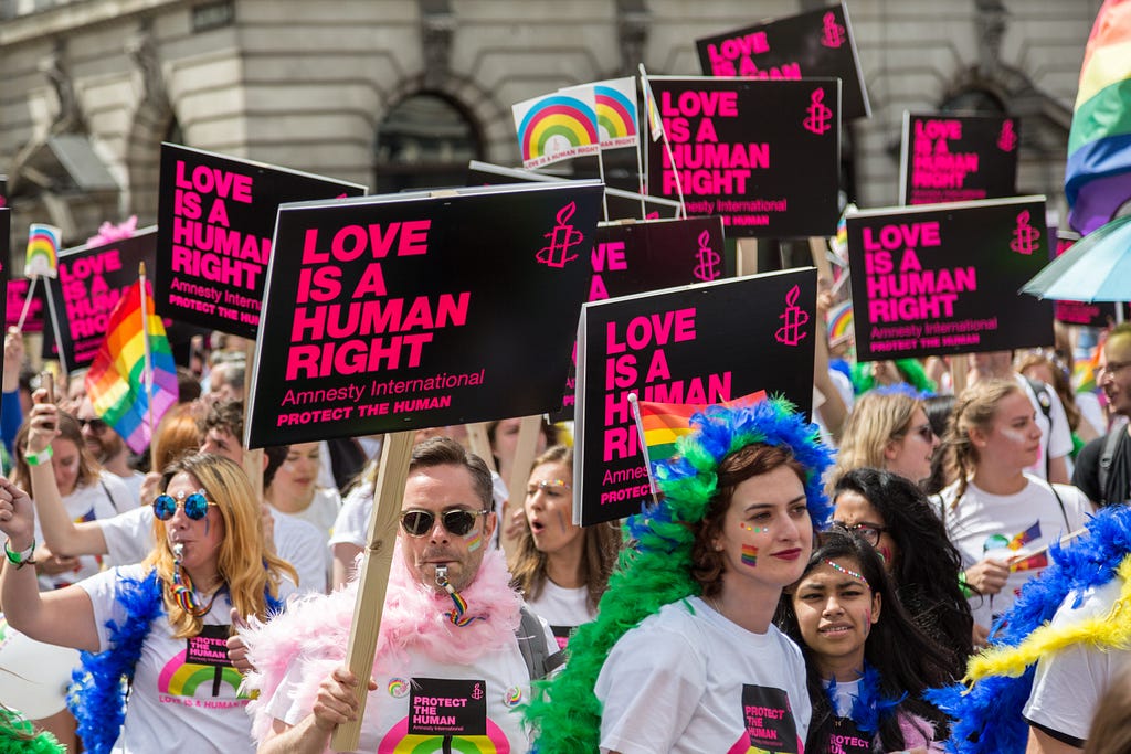 A group of LGBTQ activists holding Amnesty International signs reading “Love is a Human Right”