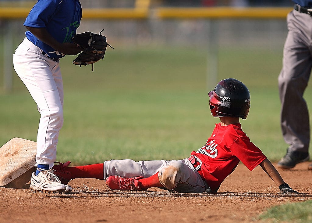 A child sliding into home plate while playing baseball