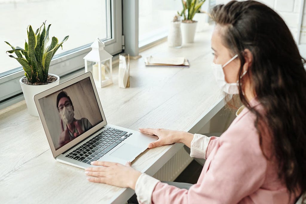 A man and a woman on a video conference call, both wearing face masks