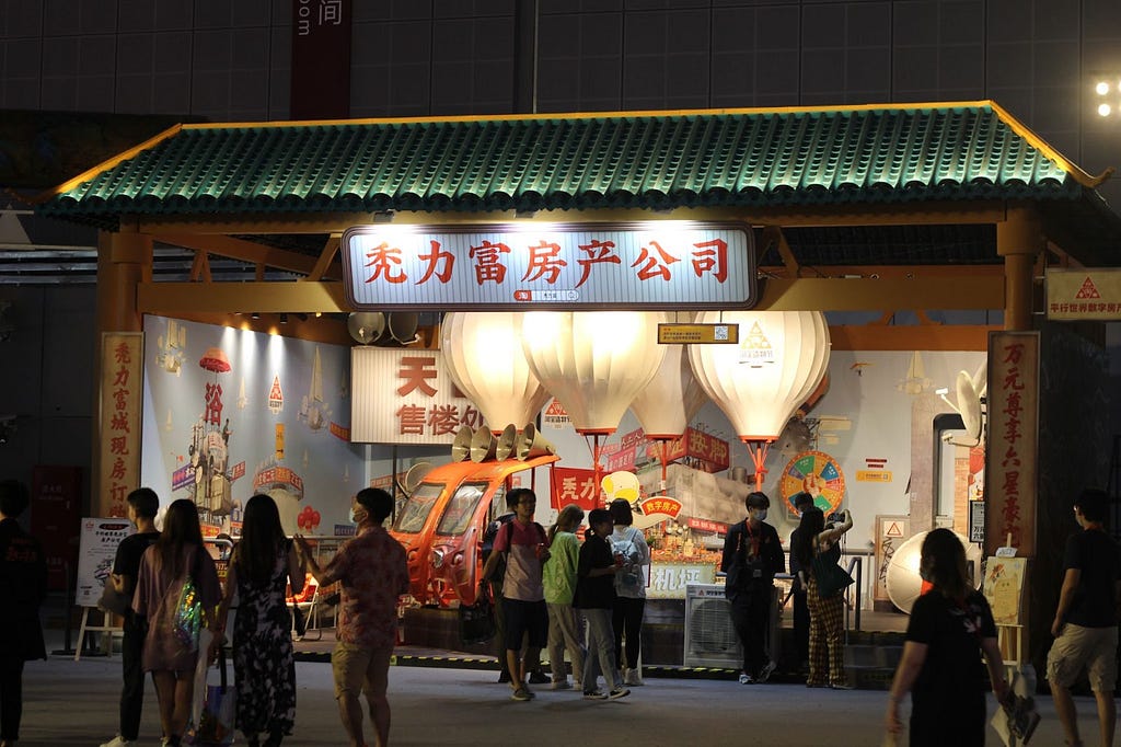 Picture of the booth with the placard reading “Too Rich Real Estate Agency” in Chinese
