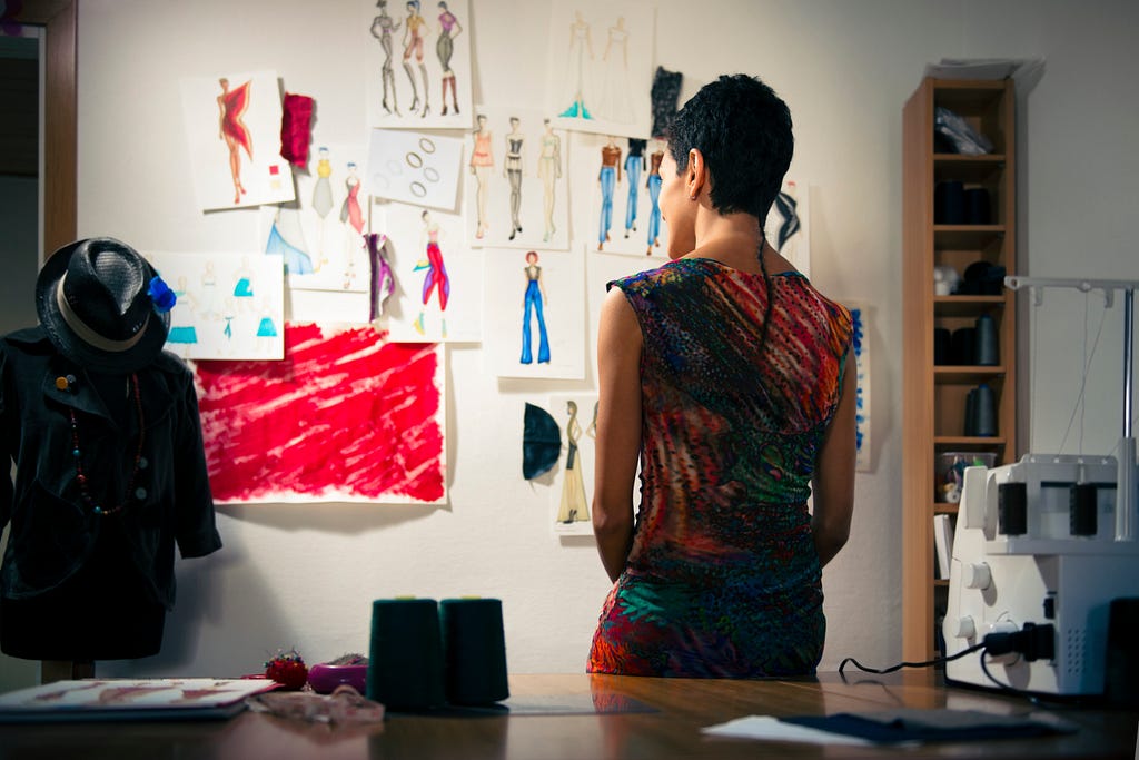 Female fashion entrepreneur contemplating drawings in studio. 