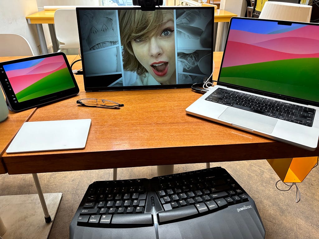 Work desk with laptop, portable external monitor, iPad Mini, Apple Trackpad, keyboard in lap