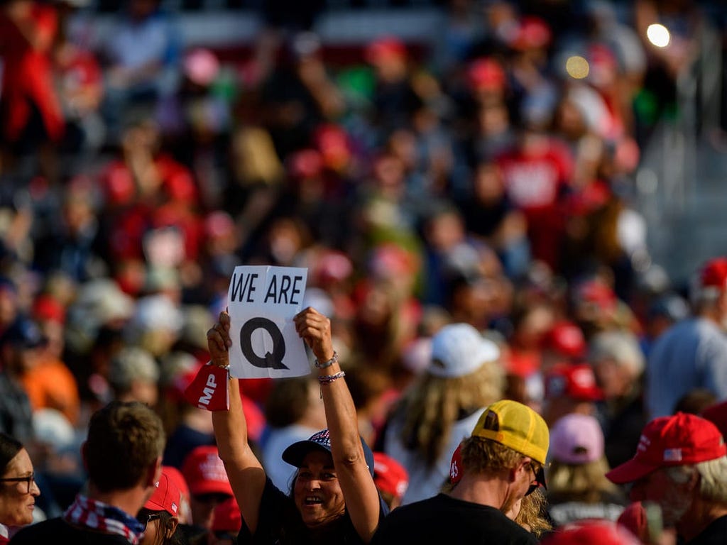 A person with a QAnon sign at a rally.