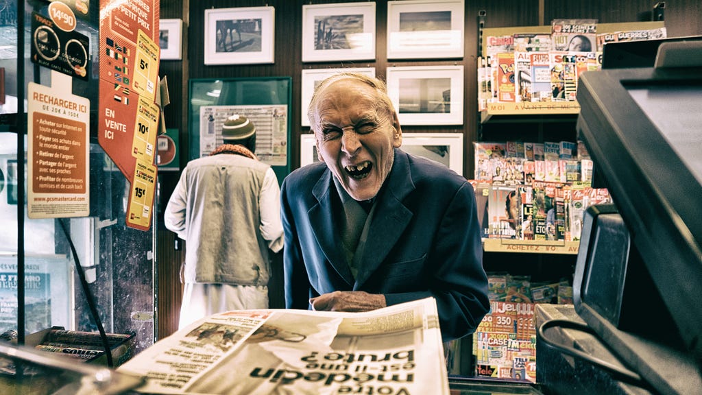 An old man buys a newspaper and laughs happily.