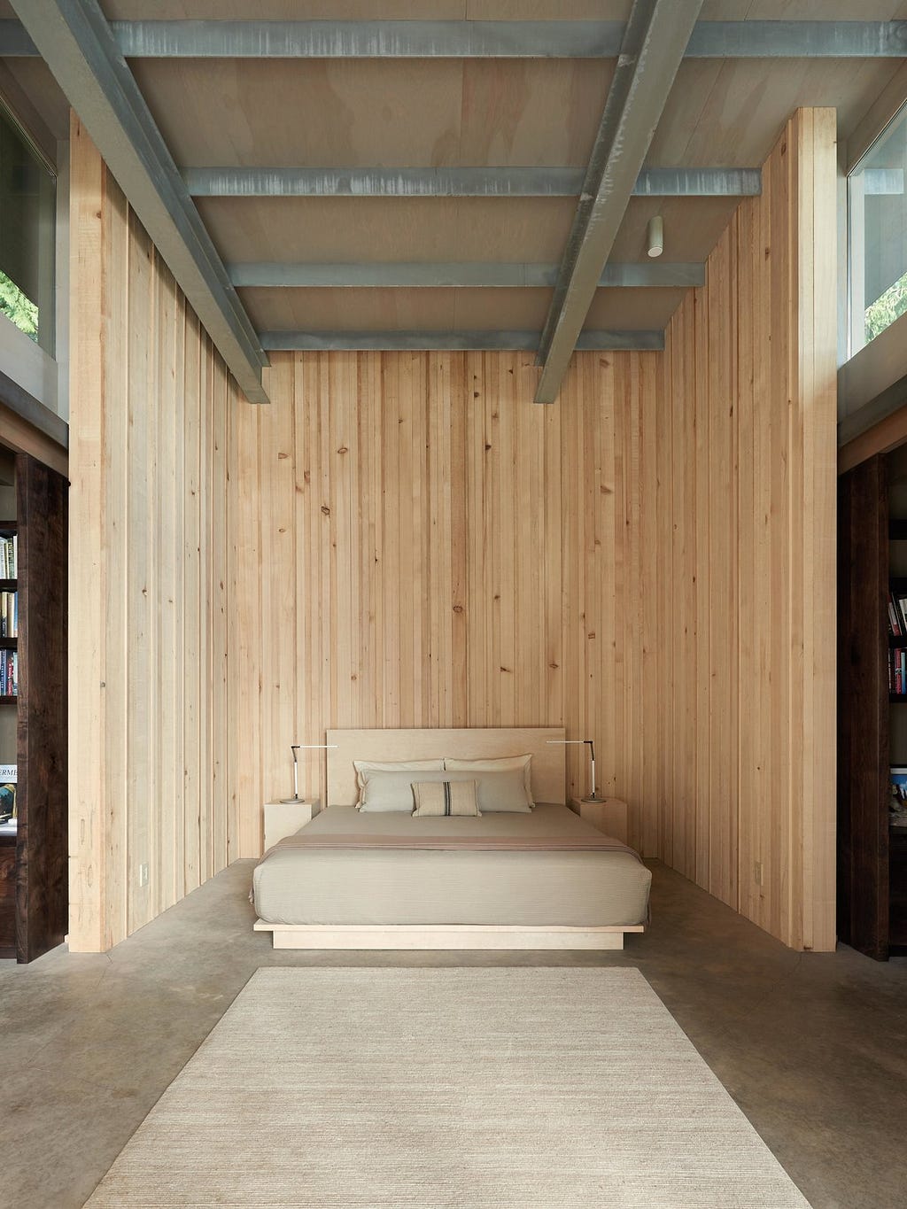 Bedroom, Concrete Floor, Rug Floor, Ceiling Lighting, Bed, Night Stands, and Table Lighting In 2014, a master bedroom and two guest rooms were added, as well as a library that also works as circulation, increasing the square footage of the retreat to 2,400 square feet.&nbsp;