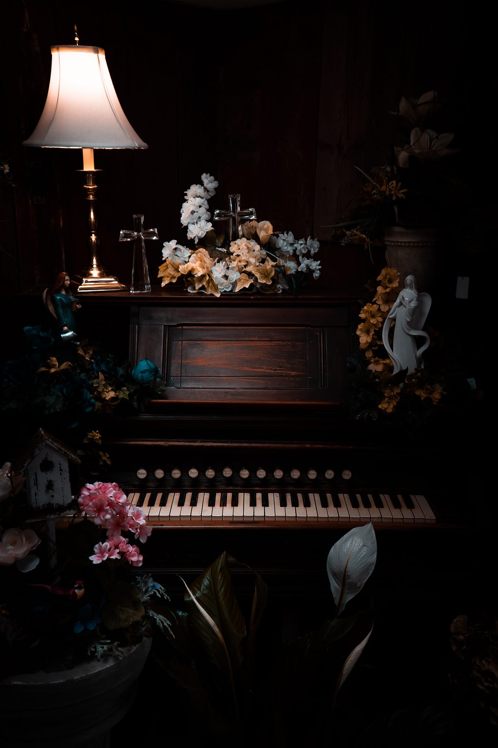 Romantic setting of flowers on piano and lamp.