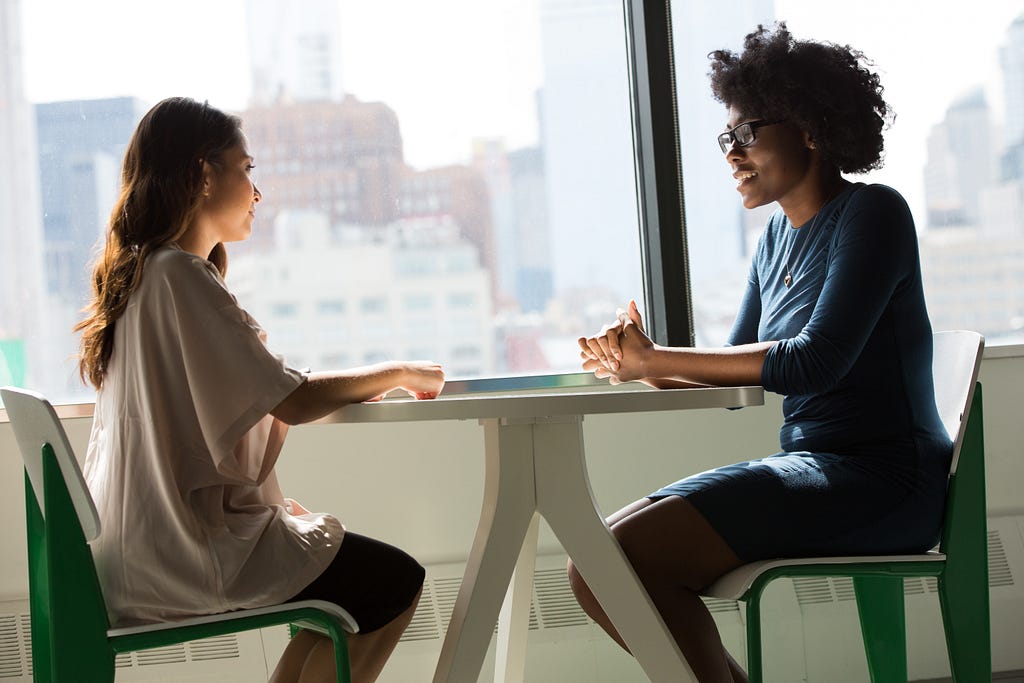 Two women talking to one another around a table