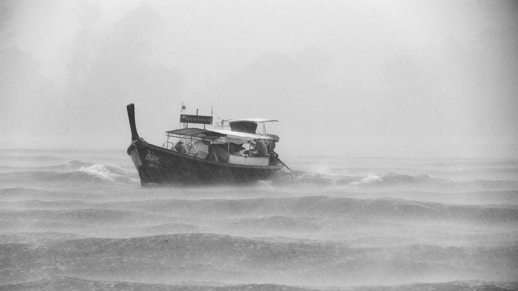 A small fishing boat is caught in a rain storm at sea.