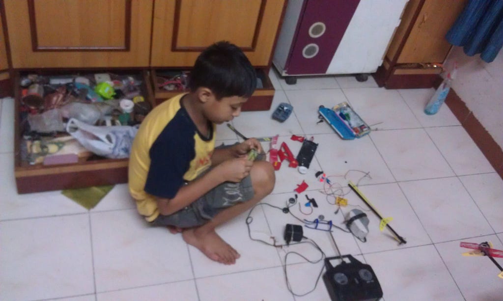 A small boy playing with damaged Laptop Battery.