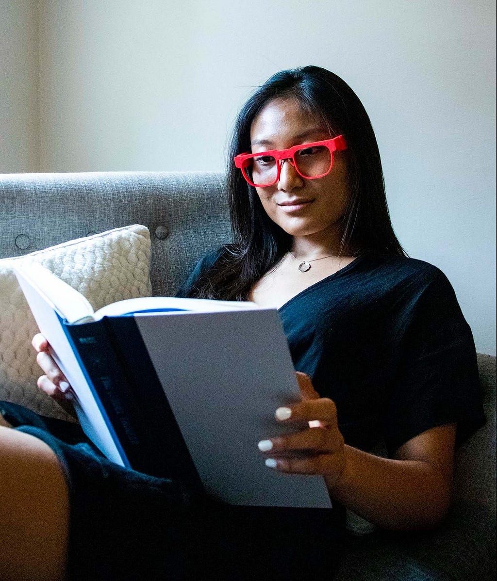 Woman wearing AttentivU glasses while reading a book.