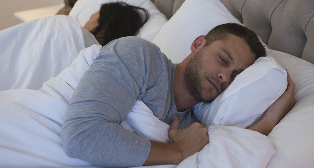 Upset boyfriend lying in bed contemplating relationship