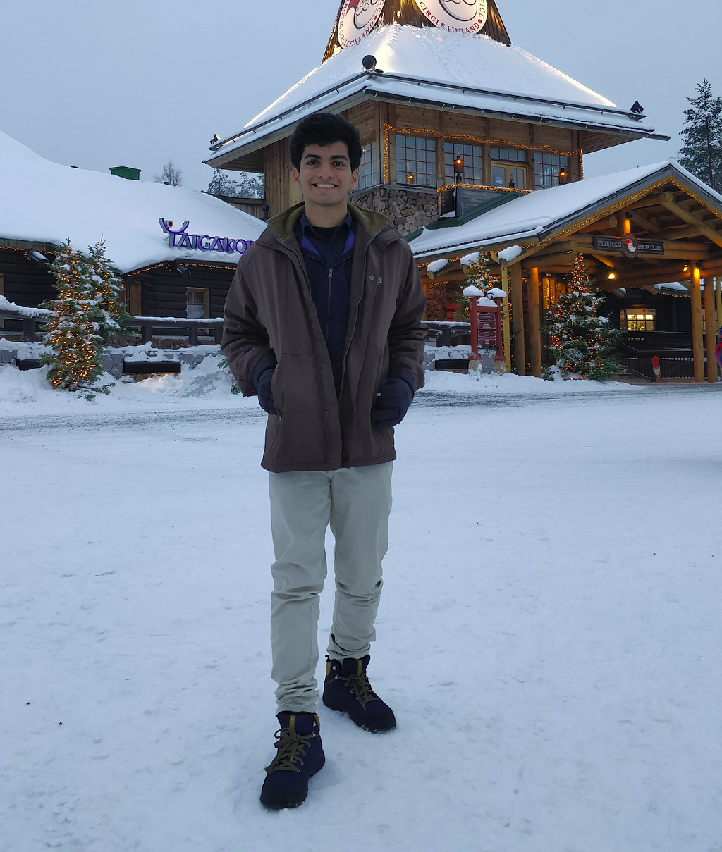 A young person stands in a snowy landscape, smiling for the camera.