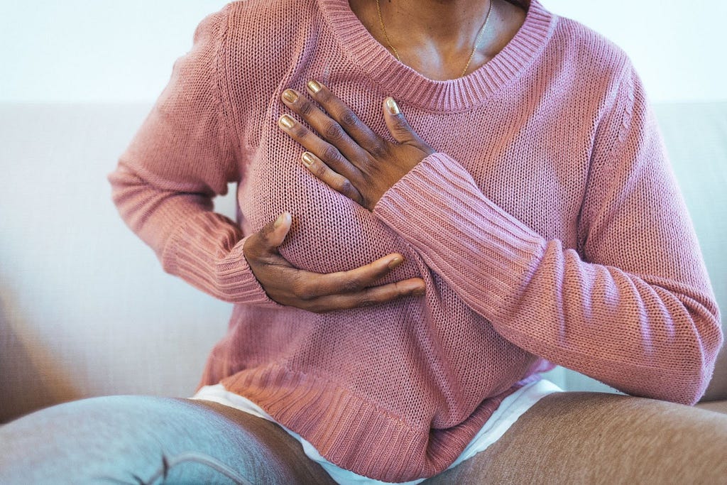Woman doing self-breast exam at home, underscoring the importance of genetic risk assessments for cancer — Invitae blog