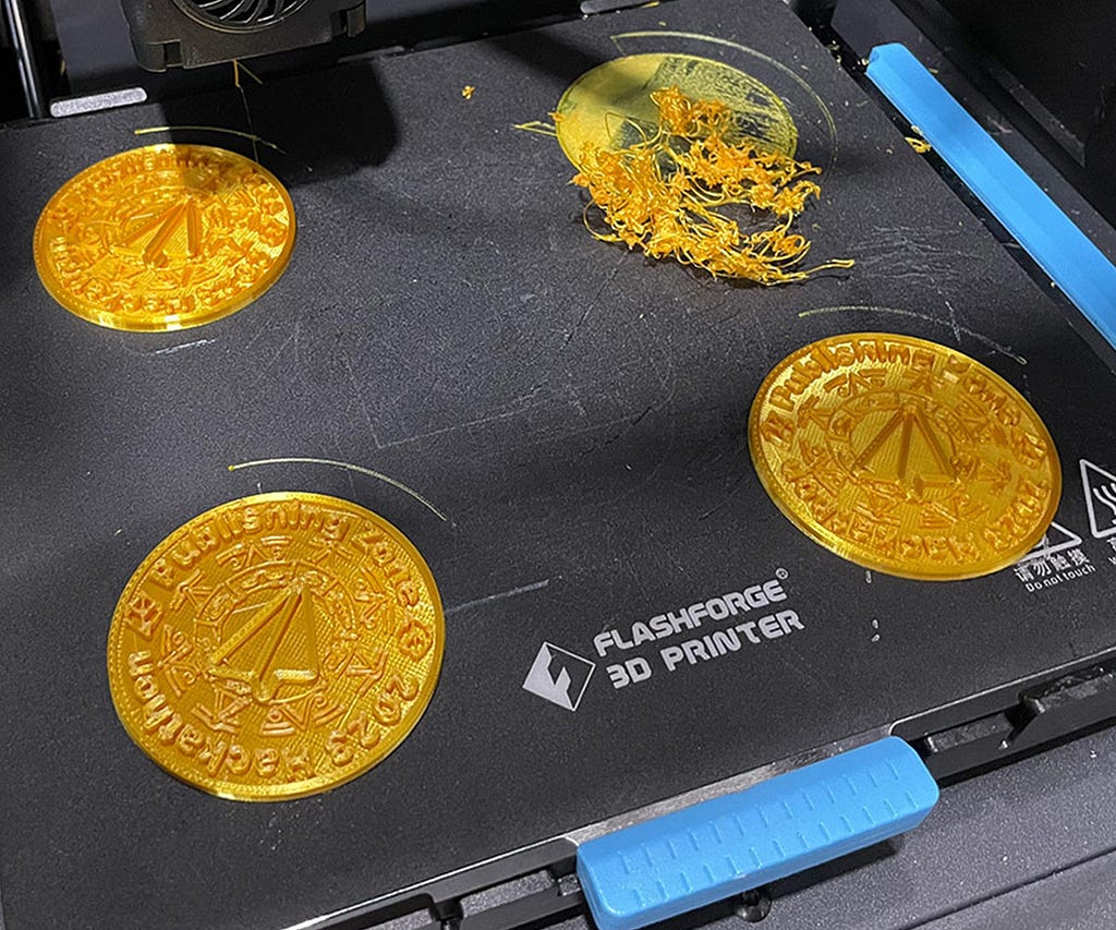 3 successfully printed coins and a mess of plastic spaghetti where the 4th should have been.