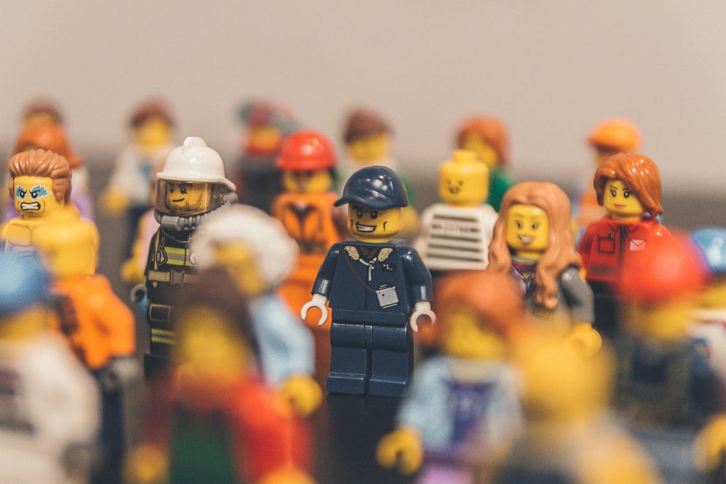 Different Lego people figures dressed in various outfits standing facing forward in a group.