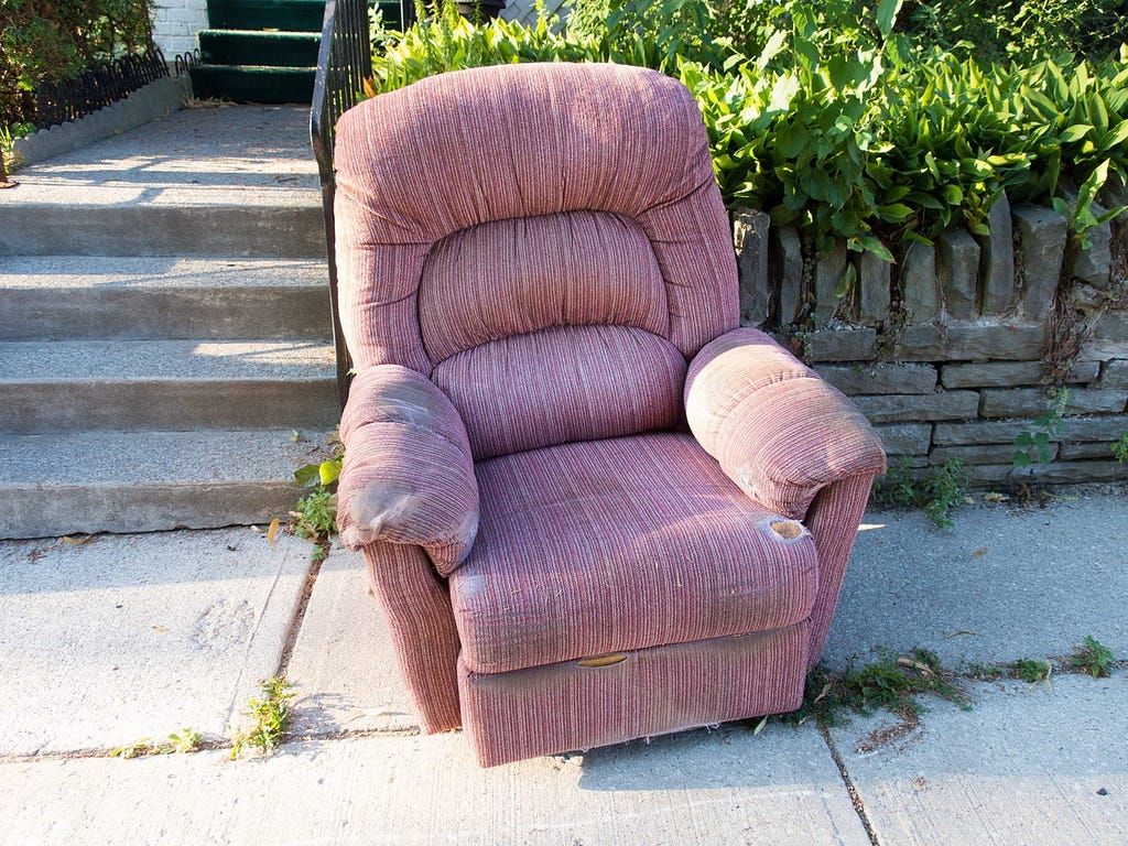 An old chair that was kicked to the curb.