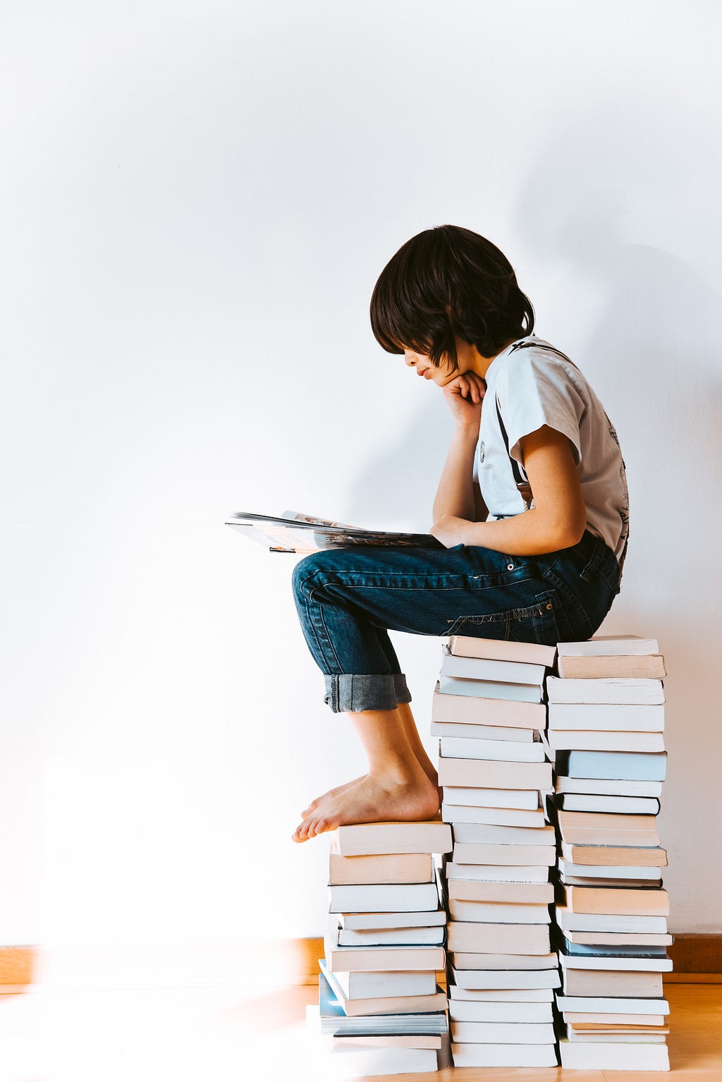 Kid sitting on a pile of books and reading