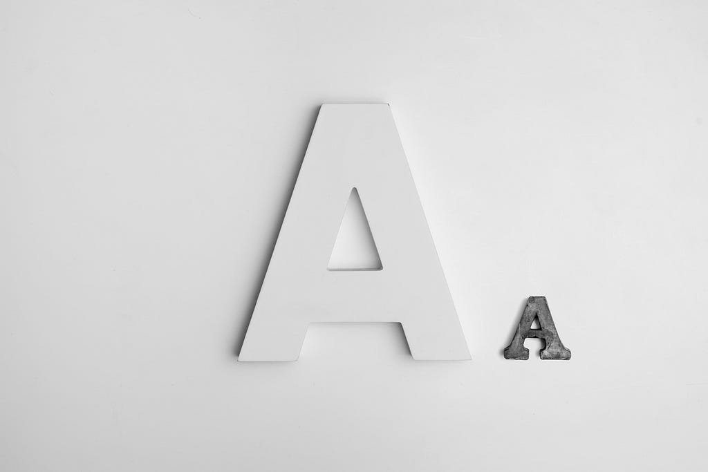 Two letter As on a white background. One A is white, large, and sans serif. The other A is black, small, and serif. Both As are uppercase.