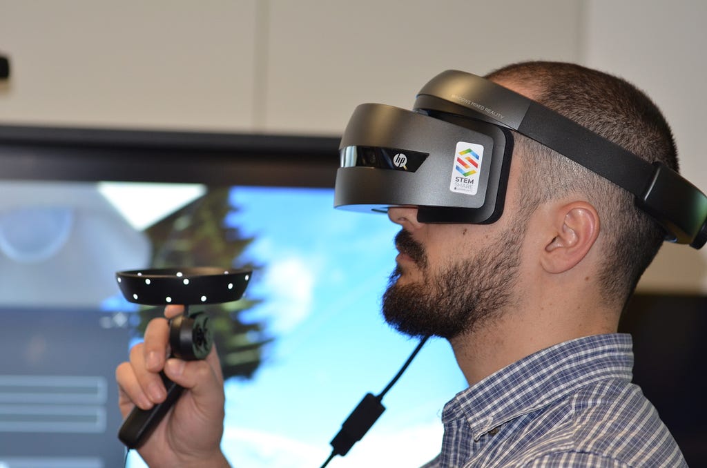 A man wearing a virtual reality headset, holding a controller.