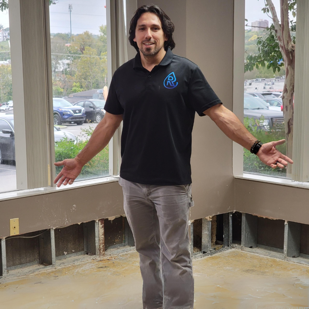 Water Damage Restoration Employee on Jobsite after performing a one foot flood cut to gain access behind drywall for dehumidifier and chemical mold remediation.