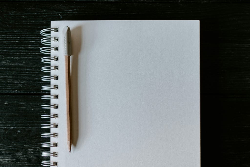 A blank spiral notebook page with a pencil on the left