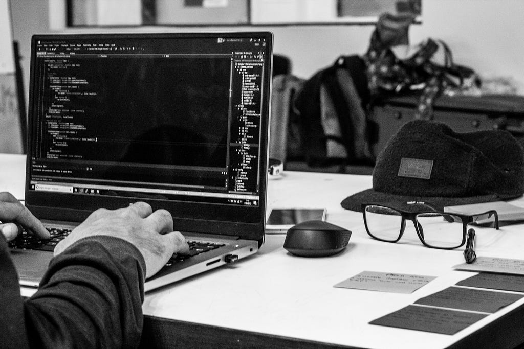 Person typing programming code on a laptop on a computer