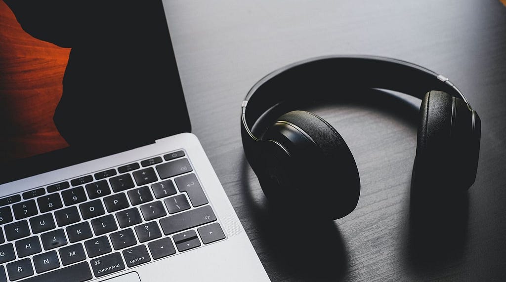 Bluetooth headphones beside a laptop