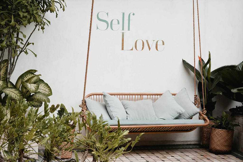 A picture of a swing with a sign that says self love above it