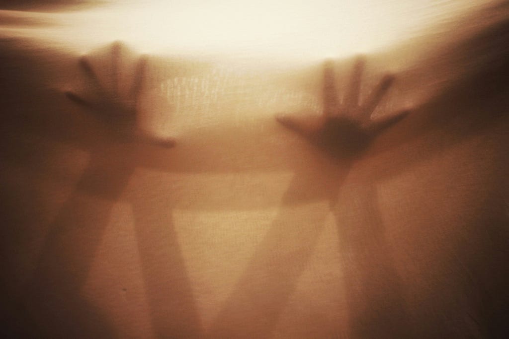 Sepia tone image of two blurry pairs of hands crossing each other