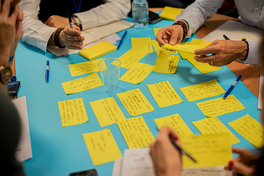 People on the table discussing ideas by writing them down on yellow sticky notes