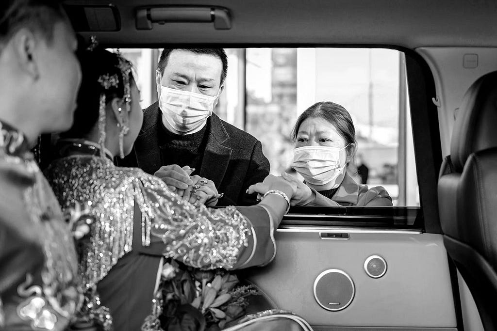 A couple talk to individuals through a car window.