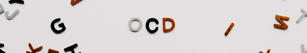 A white background with three cut out felt letters spelling “OCD”.