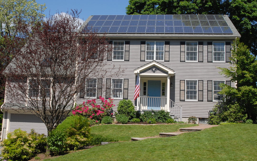 view of a two-story building with an American flag on the roof of which solar panels are placed