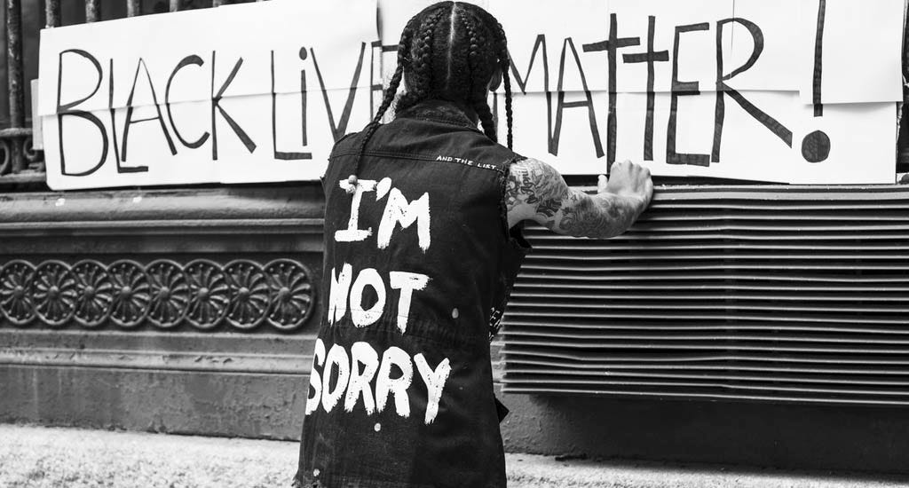 Protester standing in front of Black Lives Matter sign 