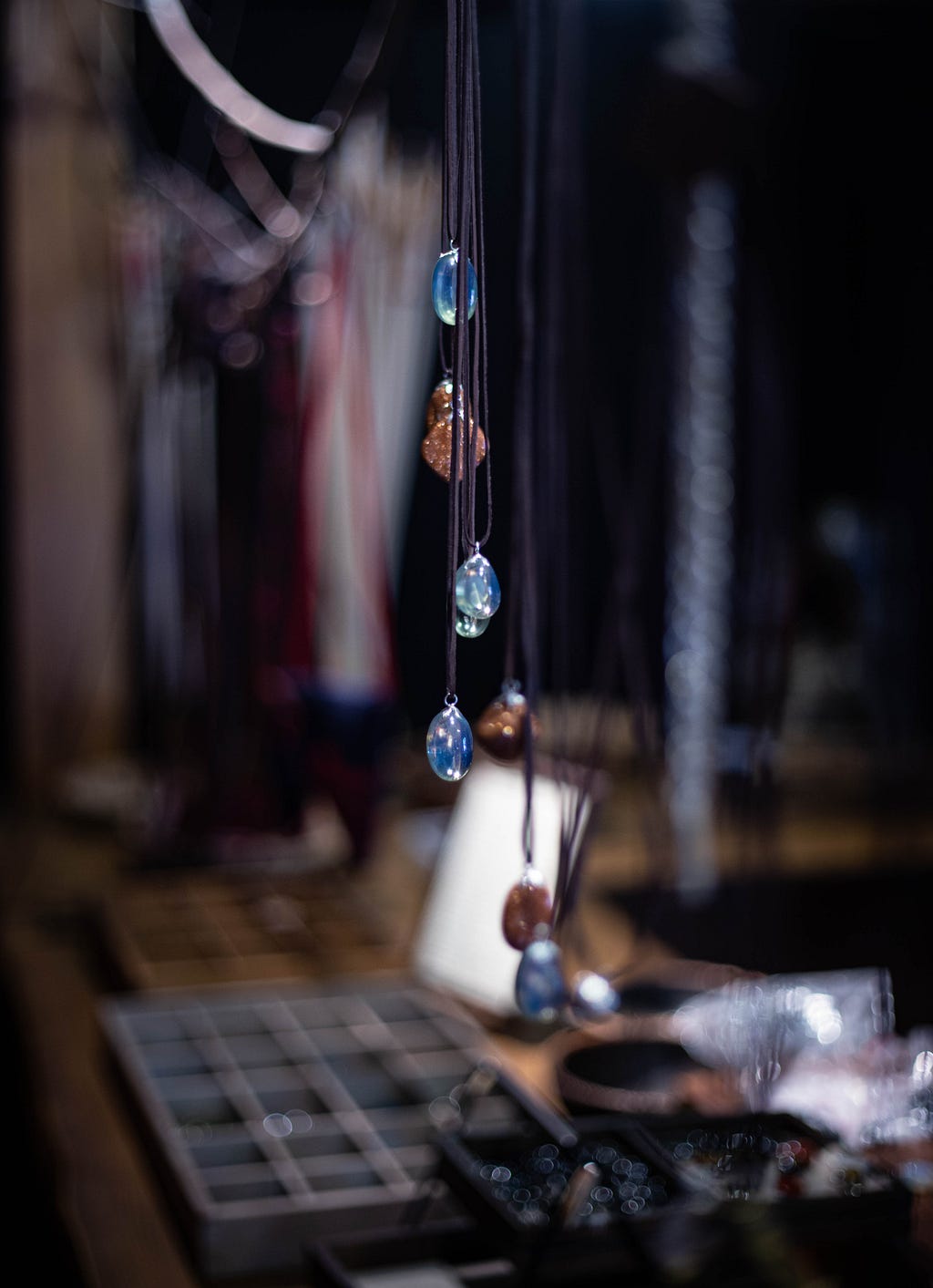 Necklaces with gemstones dangling over a table full of assorted items.