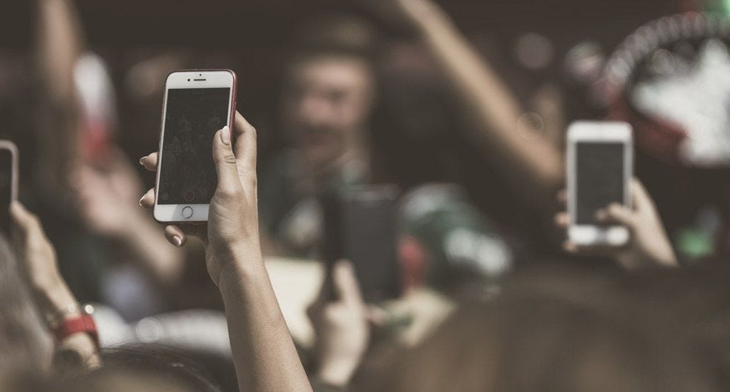 Crowd of consumers raising iPhones in air