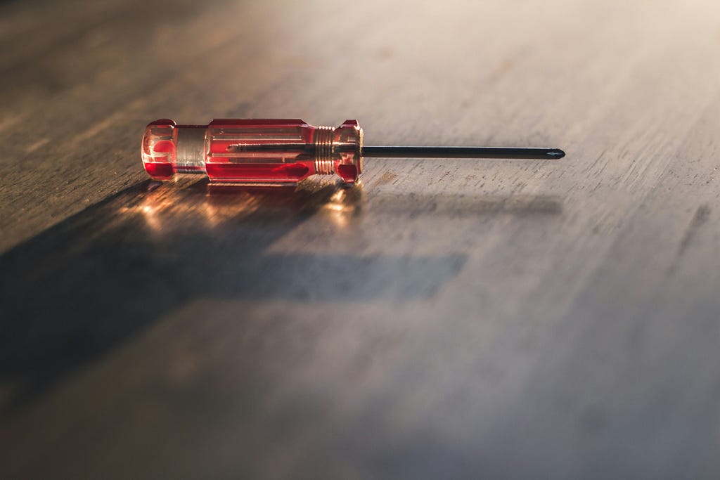 A color photograph of a single screwdriver with a wood table background.