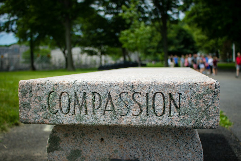 A stone bench with the word ‘compassion’ etched into the side.