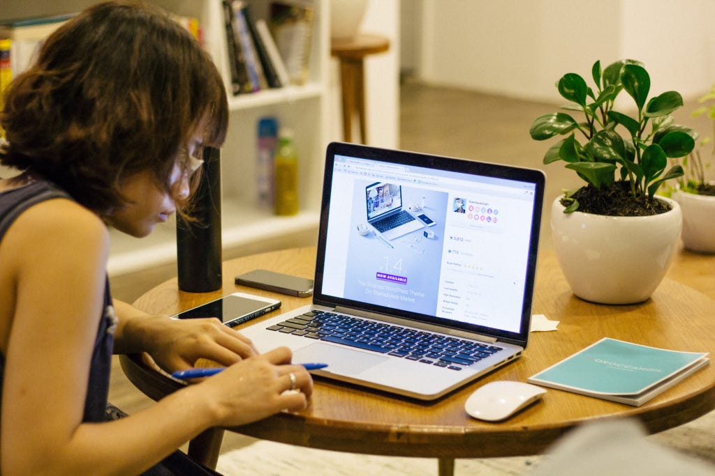 Sitting at a table a girl browses the internet on a Macbook