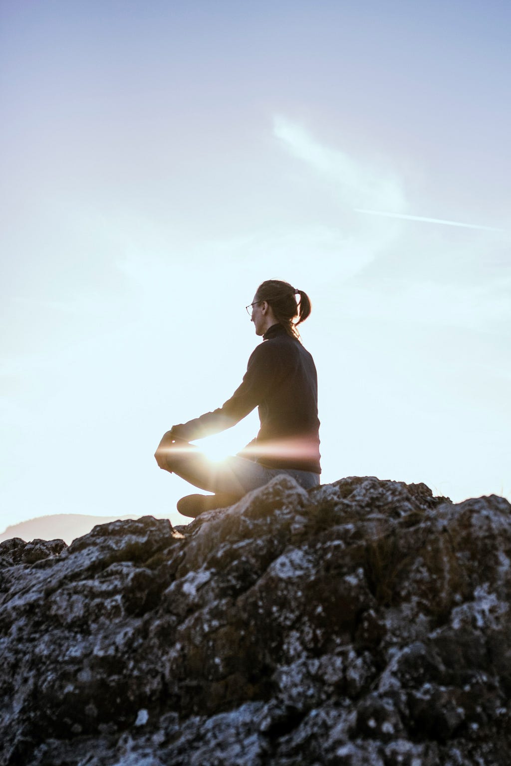 A woman meditating on the rocks
