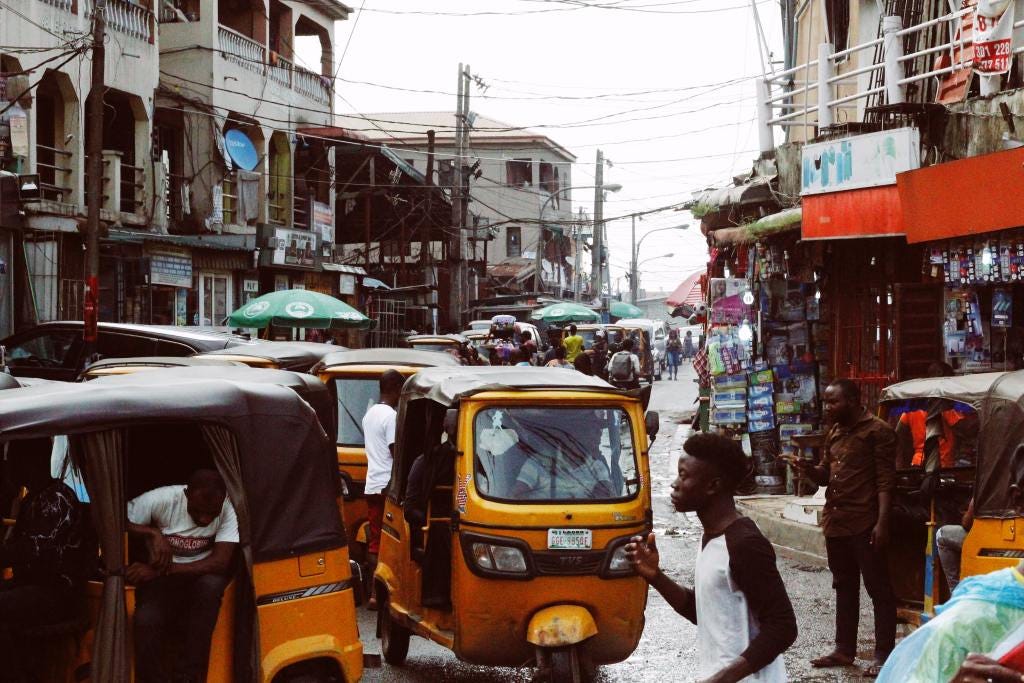 Busy Lagos Street with yellow tricycles and shops