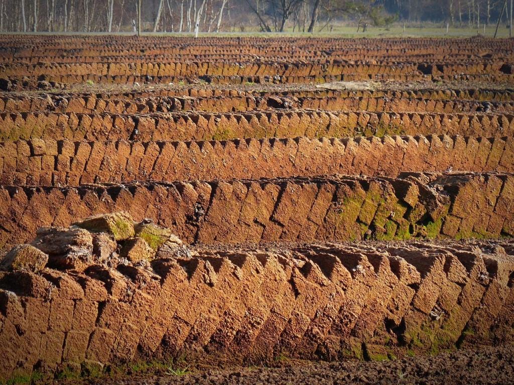 Rich brown peat cut into slices across a whole landscape