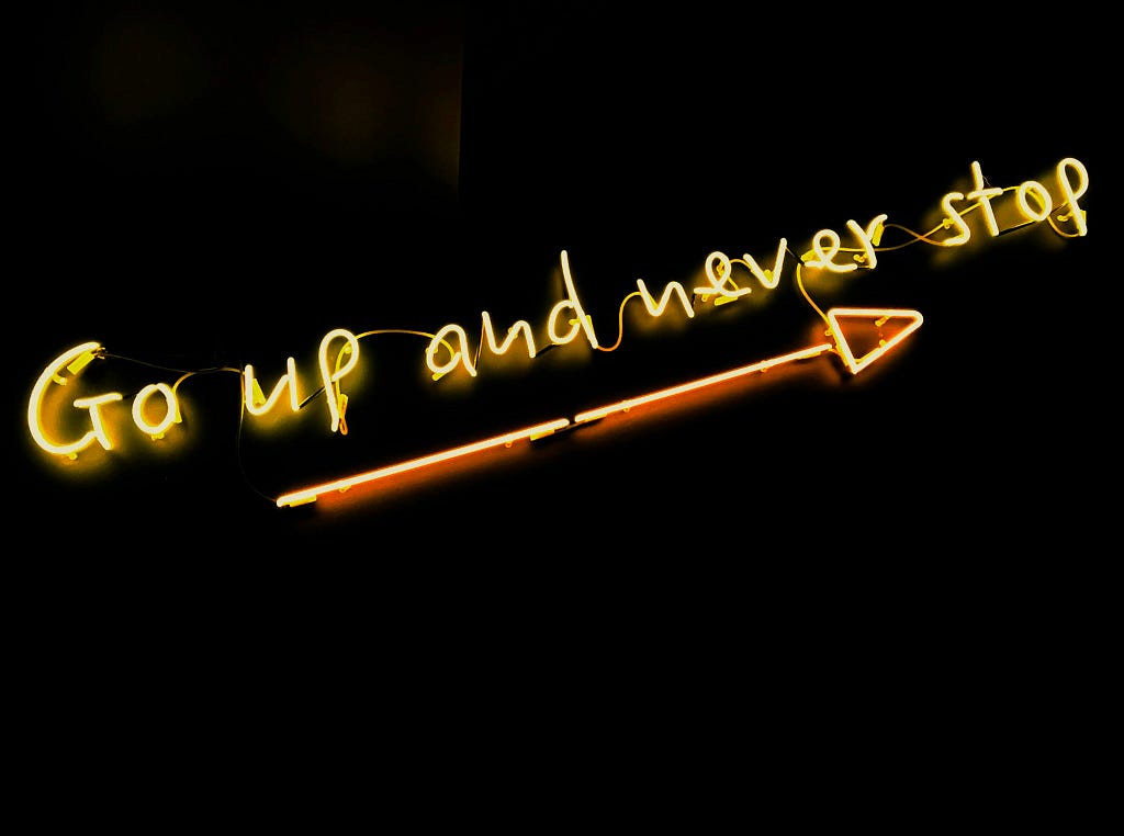 The saying “Go up and Never Stop” with an arrow on the bottom all in neon gold